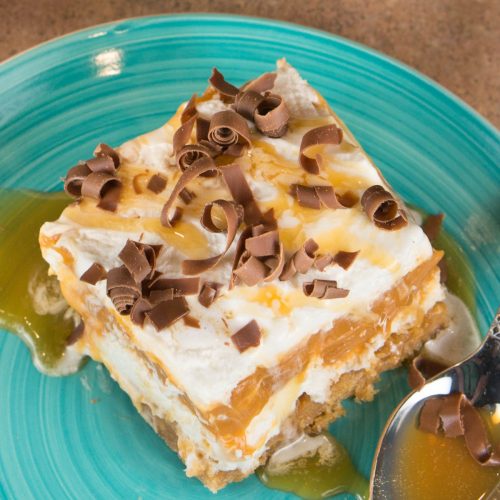 Butterscotch Lush is a 4-layer dessert of graham cracker crust, cream cheese, pudding, and whipped cream. Topped with butterscotch and chocolate shavings.