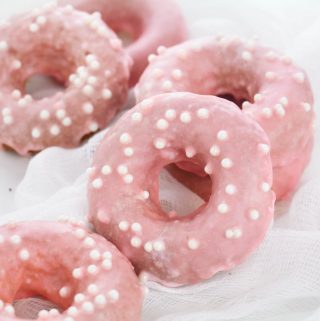 strawberry iced donuts stacked with white sprinkles