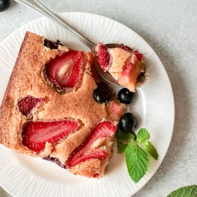 slice of triple berry cake with spoon
